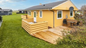 A yellow building with a wooden deck, a door, and a window. - 5 Person Holiday Home in Lemvig (Lemvig)