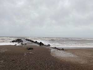 A rocky shoreline with waves crashing onto the pebbly beach. - 5 Person Holiday Home in Lemvig (Lemvig)