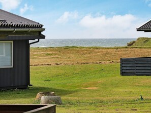 A coastal property with a small building, a grassy area, and the sea in the background. - 5 Person Holiday Home in Lemvig (Lemvig)