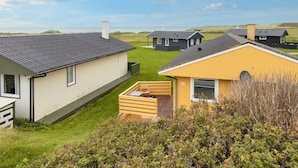A row of modern, single-story cabins with a grassy yard and a view of the sea. - 5 Person Holiday Home in Lemvig (Lemvig)