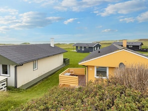 A row of modern, single-story cabins with a grassy yard and a view of the sea. - 5 Person Holiday Home in Lemvig (Lemvig)