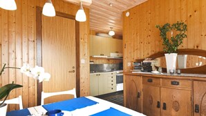 A wooden interior with a dining table set for two, a kitchen area, and a potted plant. - 4 Person Holiday Home in Brastad-by Traum (Brastad)