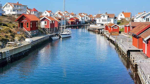 A canal with houses on either side, a boat docked in the middle, and a wooden pier with a ladder. - 4 Person Holiday Home in Brastad-by Traum (Brastad)