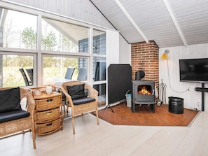A cozy room with wicker furniture, a fireplace, and a TV.