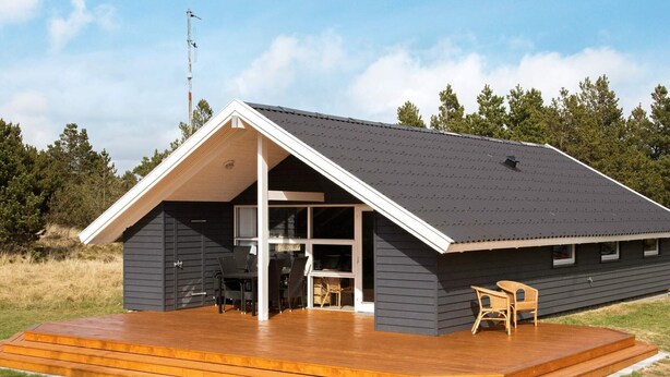 Ein modernes Haus mit einer großen Terrasse, einer überdachten Veranda und einer Garage.