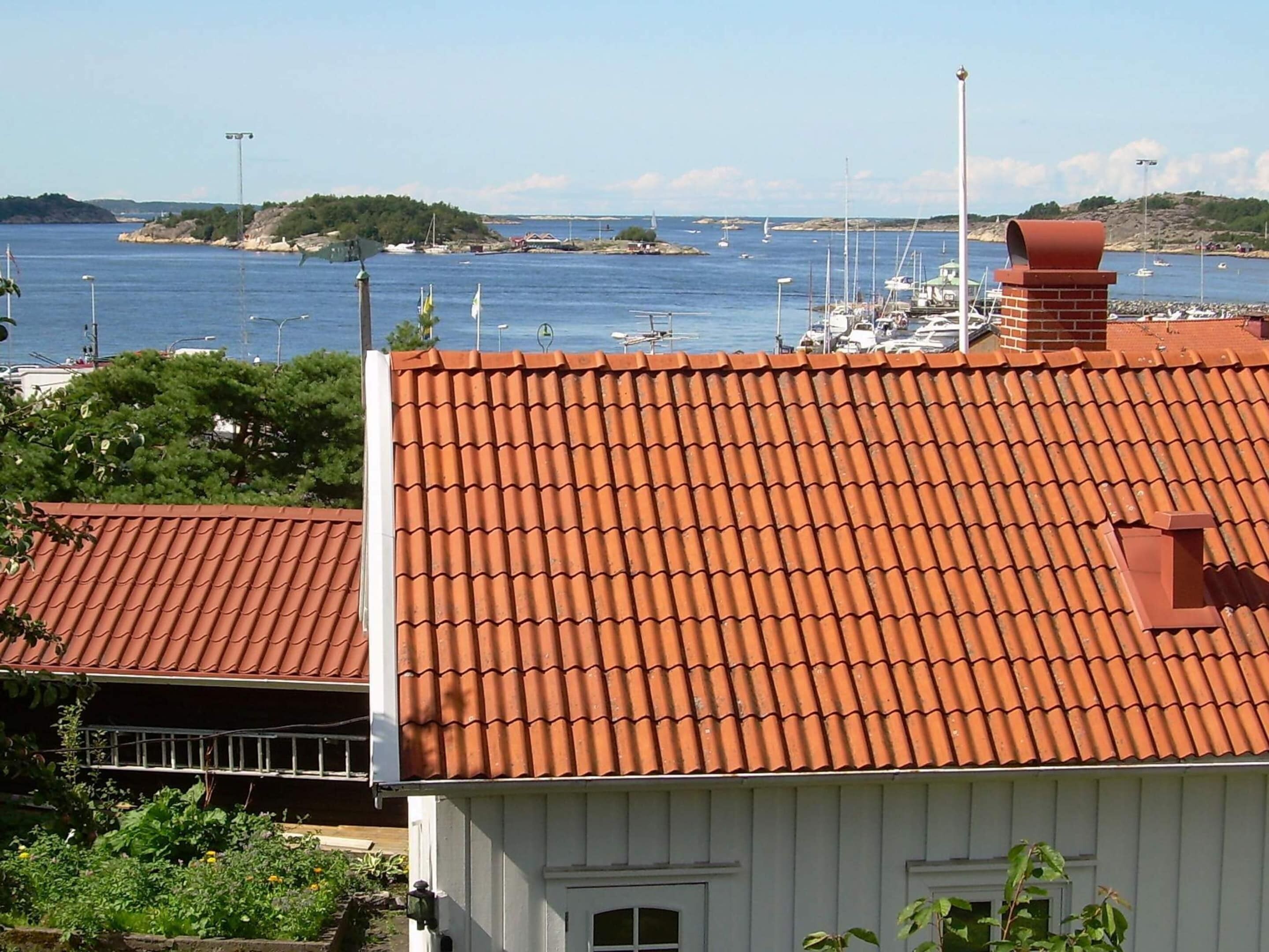 A coastal building with a red-tiled roof, white walls, and a small window.