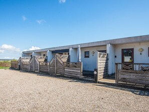 A building with a gravel driveway and wooden gates. - 4 Person Holiday Home in Romo (Rømø)