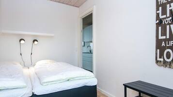 A bedroom with two beds, a nightstand, and a wall-mounted light fixture.