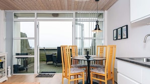 A modern kitchen with a dining area, large windows, and a view of the outdoors. - 4 Person Holiday Home in Romo (Rømø)