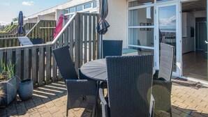 A patio with wicker furniture, a table, and a wooden deck. - 4 Person Holiday Home in Romo (Rømø)
