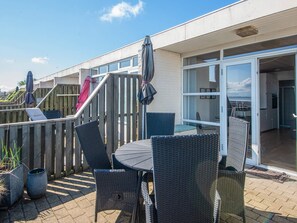 A patio with wicker furniture, a table, and a wooden deck. - 4 Person Holiday Home in Romo (Rømø)