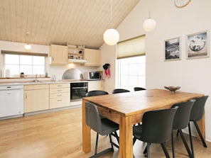 A modern kitchen with wooden cabinets, a dining table, and chairs.