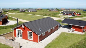 A residential area with houses featuring red exteriors and grey roofs, arranged on a grassy landscape with a clear sky. - Picturesque Holiday Home in LÃ¸kken near Sea (Lokken)