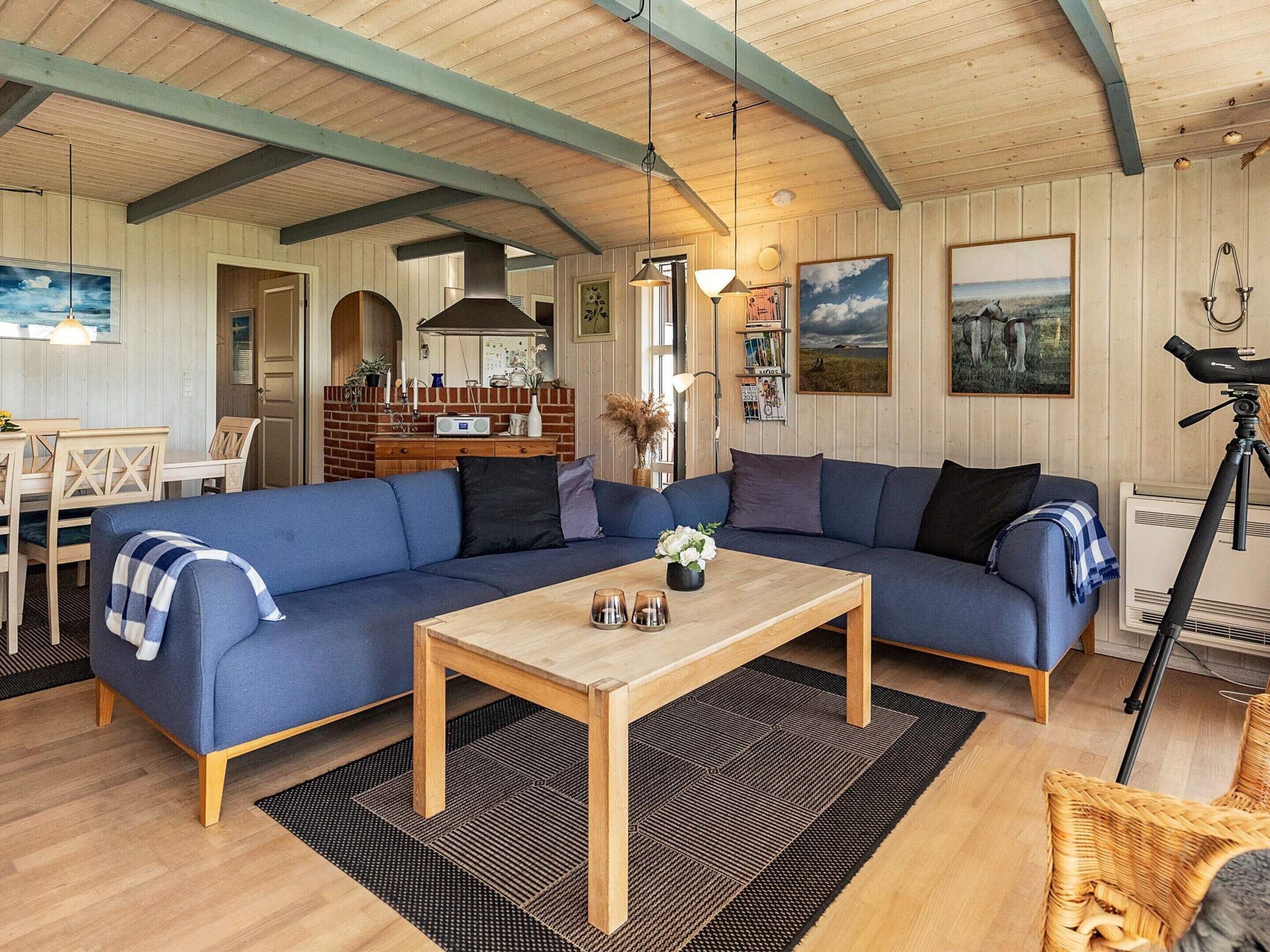 Un salon chaleureux avec un canapé bleu, une table basse en bois et un coin repas comprenant une table et des chaises.