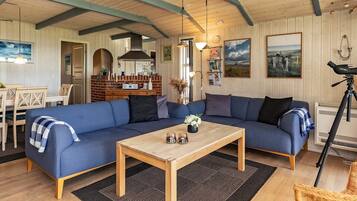 Un salon chaleureux avec un canapé bleu, une table basse en bois et un coin repas comprenant une table et des chaises.