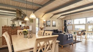 A spacious living area with a dining table, chairs, a sofa, and a view of the outdoors. - 5 Star Holiday Home in Oster Assels (Øster Assels)