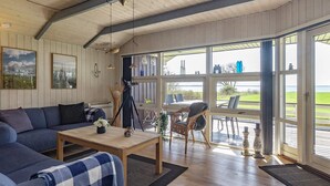 A cozy living room with a sofa, a coffee table, and a dining area with chairs and a table. - 5 Star Holiday Home in Oster Assels (Øster Assels)
