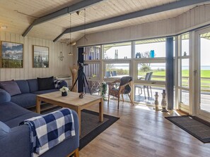 A cozy living room with a sofa, a coffee table, and a dining area with chairs and a table. - 5 Star Holiday Home in Oster Assels (Øster Assels)