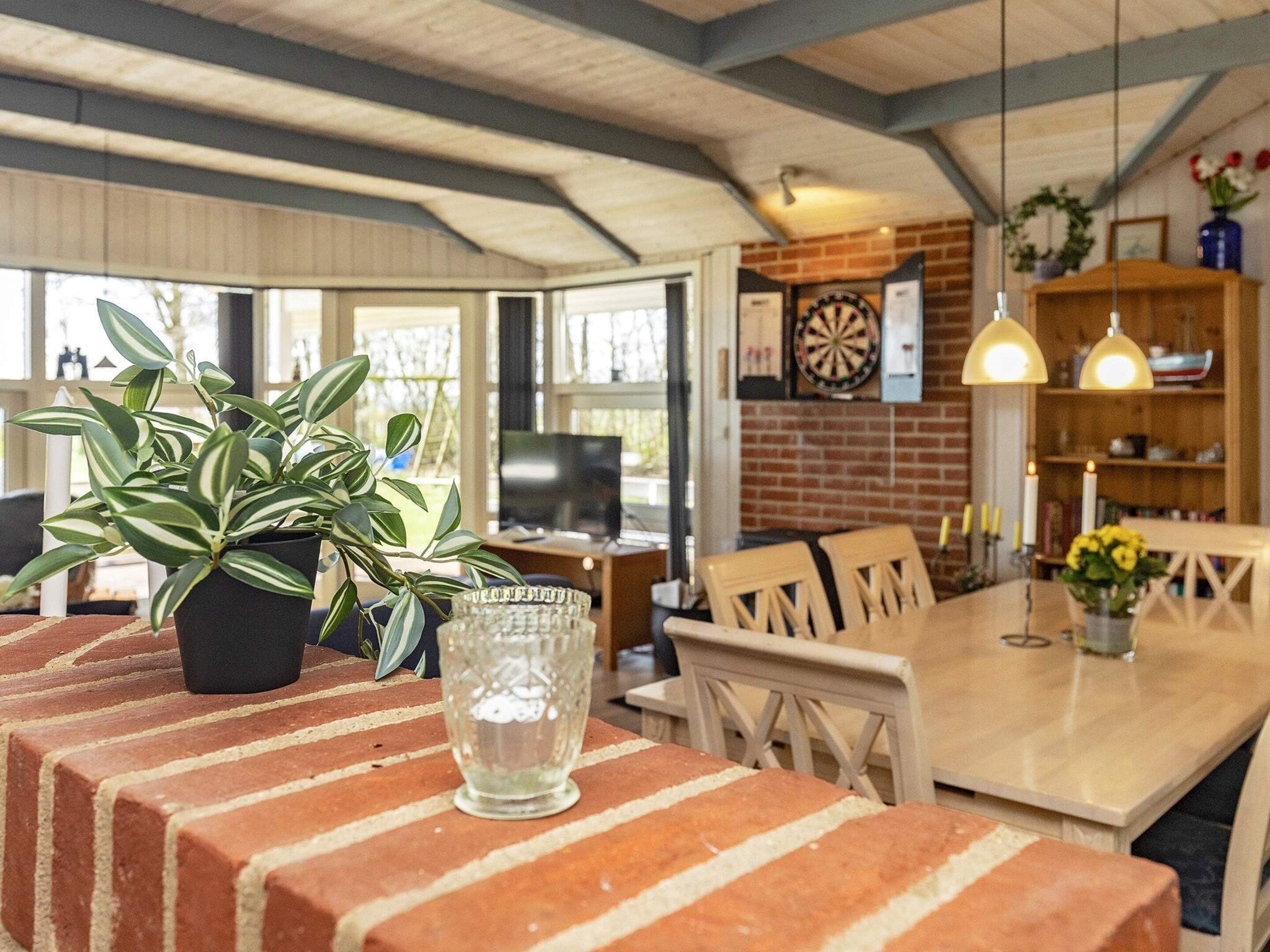 A dining area with a brick table, chairs, a potted plant, and a glass vase.