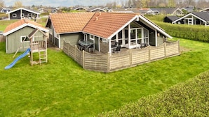 A residential area with multiple houses, a wooden deck with outdoor furniture, and a blue slide. - 5 Star Holiday Home in Juelsminde (Horsens)
