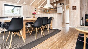A cozy wooden interior with a dining area, kitchen, and a fireplace. - 5 Star Holiday Home in Juelsminde (Horsens)