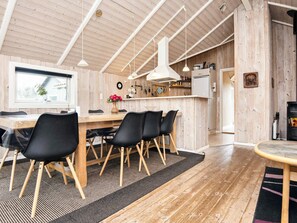 A cozy wooden interior with a dining area, kitchen, and a fireplace.