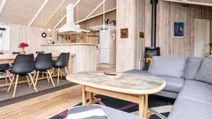 A cozy cabin interior with a dining area, a sofa, and a fireplace. - 5 Star Holiday Home in Juelsminde (Horsens)