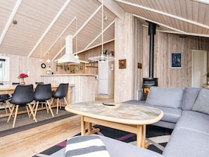 A cozy cabin interior with a dining area, a sofa, and a fireplace.