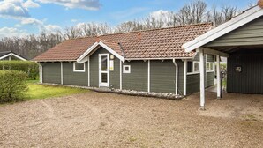 A single-story building with a brown tiled roof, a front porch, and a gravel driveway. - 5 Star Holiday Home in Juelsminde (Horsens)