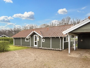 A single-story building with a brown tiled roof, a front porch, and a gravel driveway.