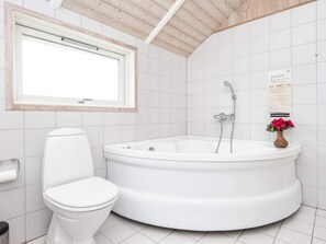A bathroom with a toilet, a bathtub, and a window.