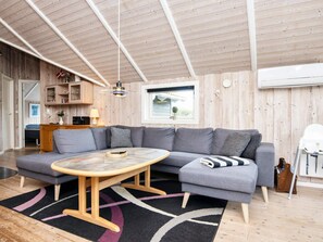 A modern living room with a sectional sofa, a round wooden coffee table, and a black and white patterned rug. - 5 Star Holiday Home in Juelsminde (Horsens)