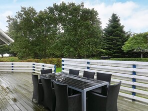 An outdoor dining area with a table and chairs, surrounded by a wooden deck and a white fence. - 5 Star Holiday Home in Hals (Hals)