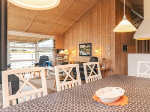 Una habitación acogedora con paredes de madera, una mesa de comedor, sillas y vistas al exterior.