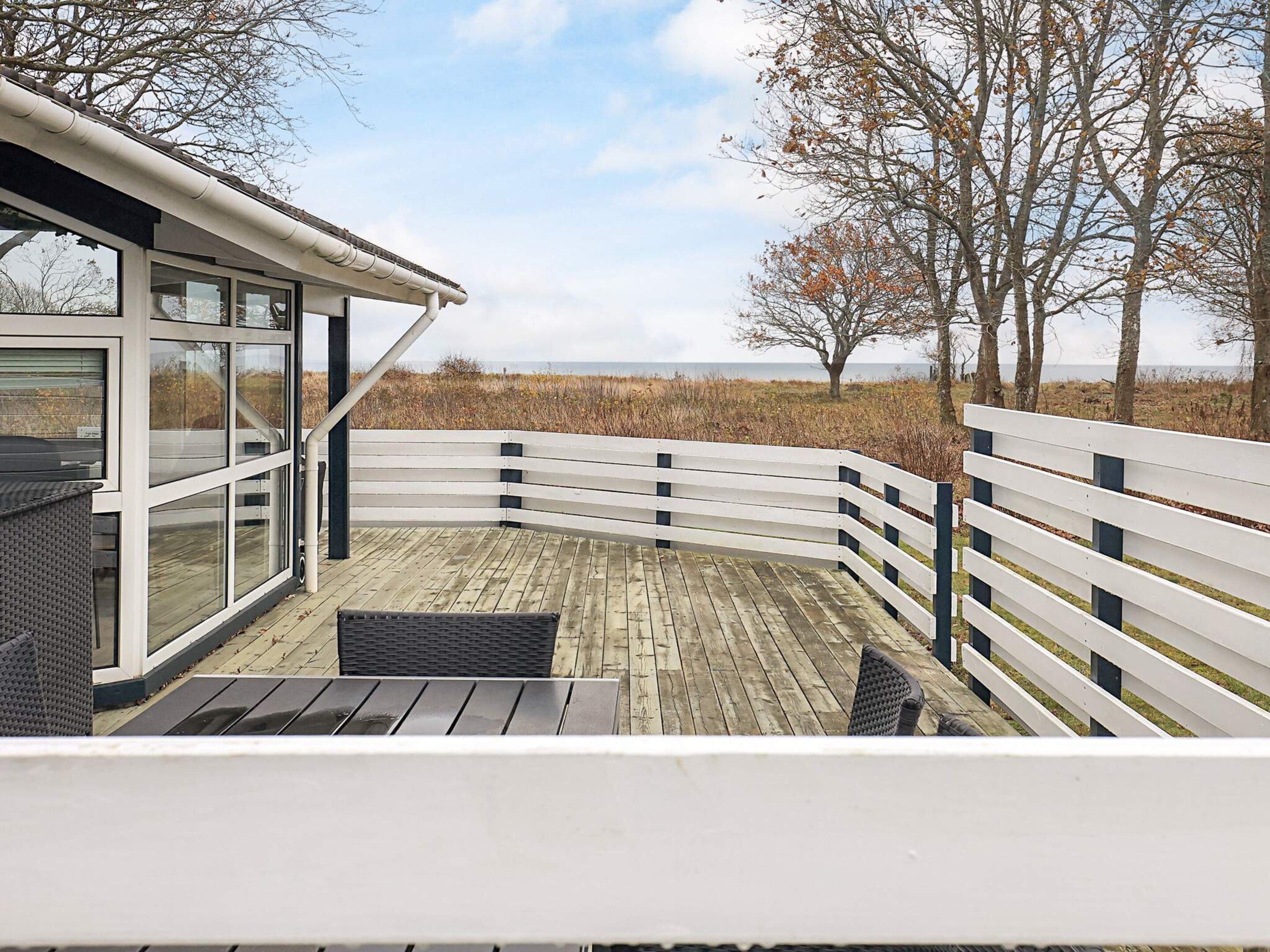 A modern outdoor deck with a curved railing, overlooking a natural landscape.