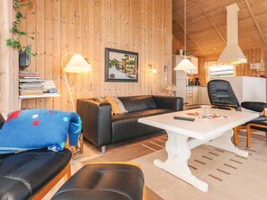 Un interior acogedor de madera con un sofá, una mesa de comedor y una zona de cocina.