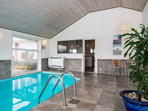 An indoor swimming pool with a view of the outside, a ceiling fan, and a potted plant. - 4 Star Holiday Home in Henne (Henne)
