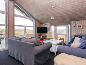A modern living room with a large window, a flat-screen TV, and a cozy seating area. - 4 Star Holiday Home in Henne (Henne)