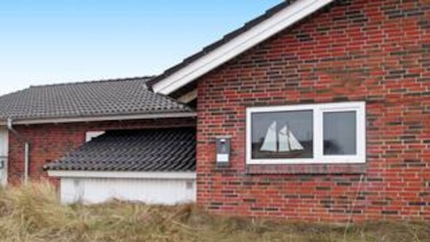 A brick house with a tiled roof, a garage, and a window with a sailboat picture. - 4 Star Holiday Home in Henne (Henne)