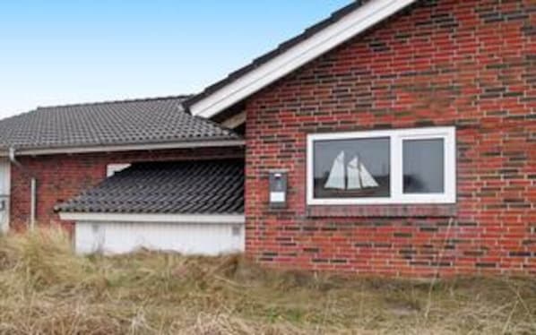 Ett hus byggt av tegel med ett tak täckt av takpannor, ett garage och ett fönster med en bild av en segelbåt.