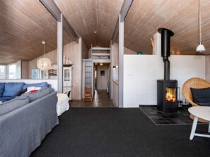 A modern interior with a sofa, a dining table, a fireplace, and a staircase leading to an upper level. - 4 Star Holiday Home in Henne (Henne)