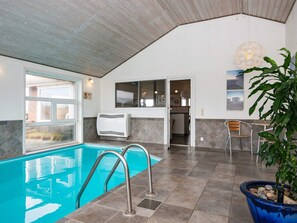 A swimming pool with a view of the outside, a ceiling fan, and a potted plant. - 4 Star Holiday Home in Henne (Henne)