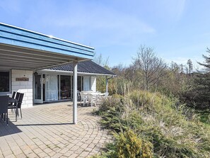 Une maison dotĂ©e dâun patio couvert, dâun coin repas avec chaises et tables, et dâune enseigne indiquant « Lisbeth Huis ».