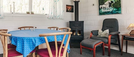 A cozy room with a round table, chairs, a sofa, a fireplace, and a painting on the wall.