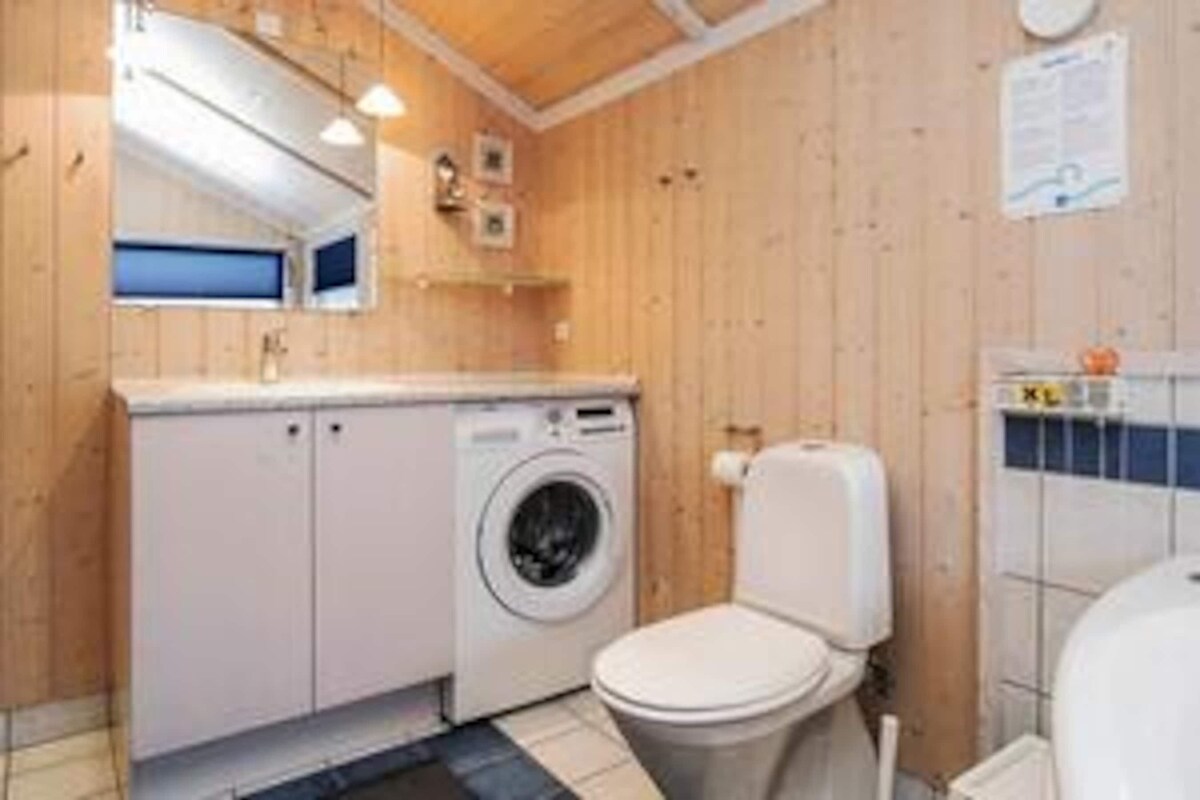 Un baño pequeño y funcional con lavadora, inodoro y un espejo sobre el lavabo.