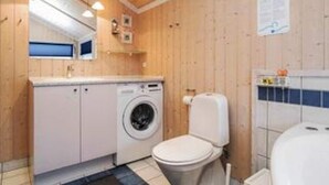 A small, compact bathroom with a washing machine, toilet, and a mirror above the sink. - 4 Star Holiday Home in Slagelse (Slagelse)