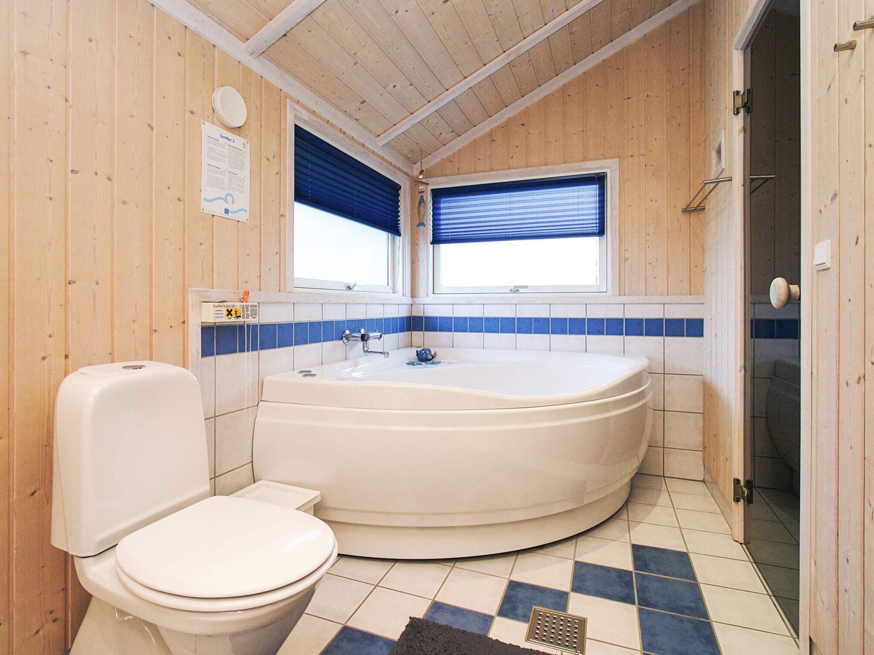 Ein Badezimmer mit Toilette, einer Badewanne und einem Fenster mit Jalousien.