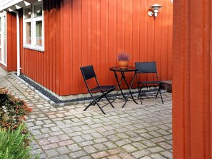 An outdoor seating area with two chairs and a table, a potted plant, and a wall-mounted light fixture.