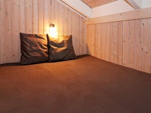 A room with a sloped ceiling, wooden walls, and a bed with two pillows.