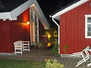A red building with a white exterior, a bench, and a chair outside.